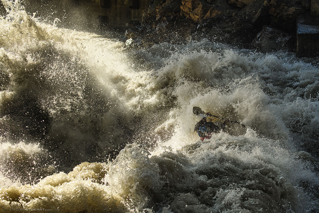 man kayaks through churning whitewater and spray