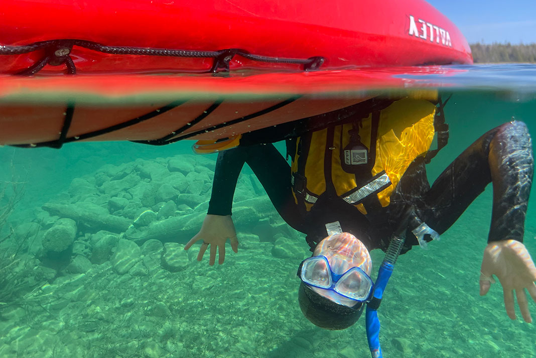 kayaker flips underwater while wearing a wetsuit