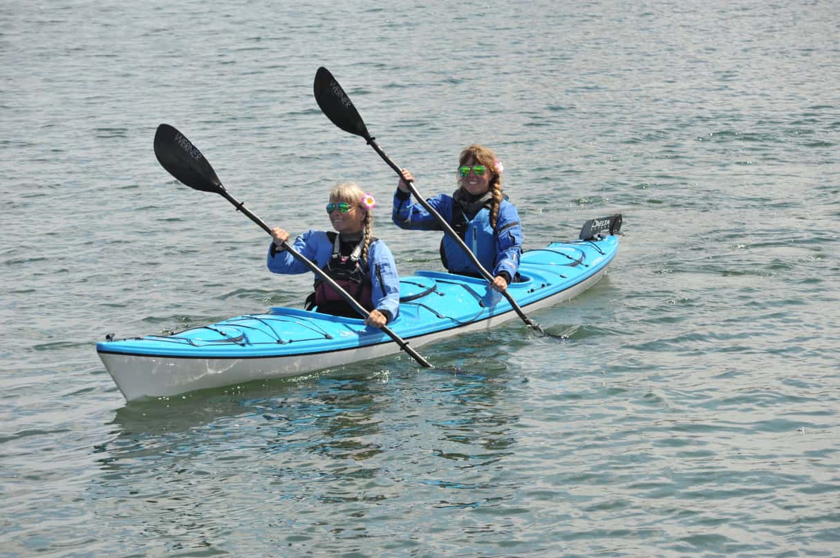 Two women paddling a tandem touring kayak.