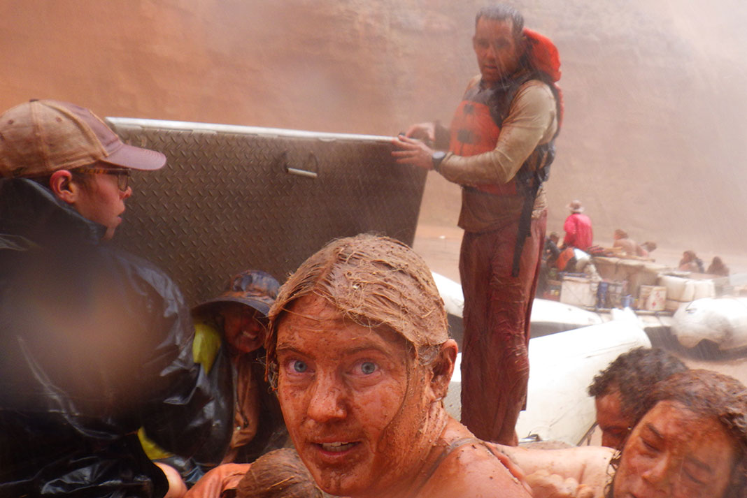 one man holds an aluminum box up to protect rafters from falling rocks during a Grand Canyon flash flood