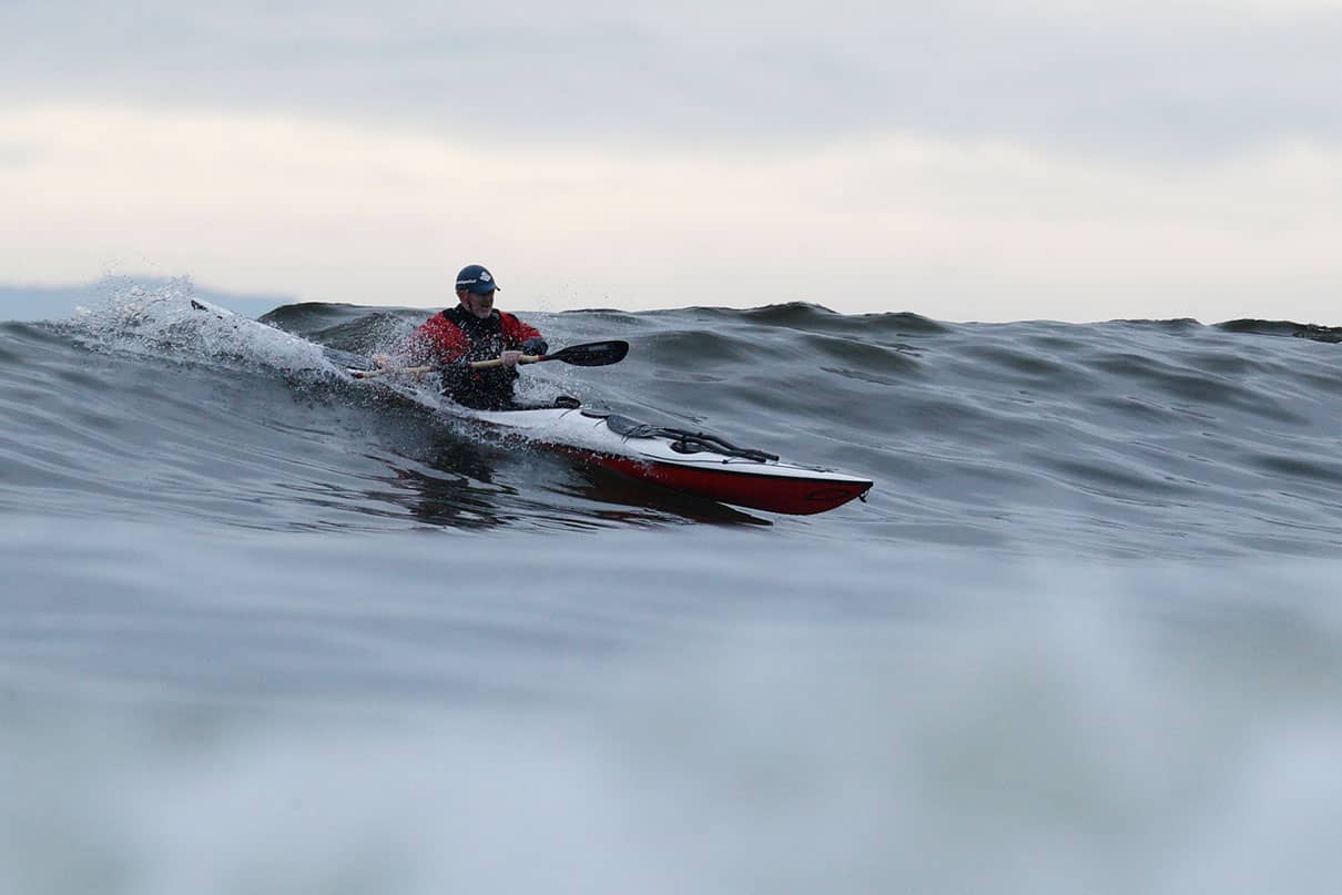 a man kayak surfing on a wave