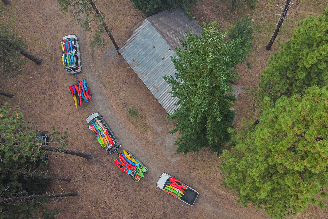 overhead photo of a pair of vans hauling many many river kayaks