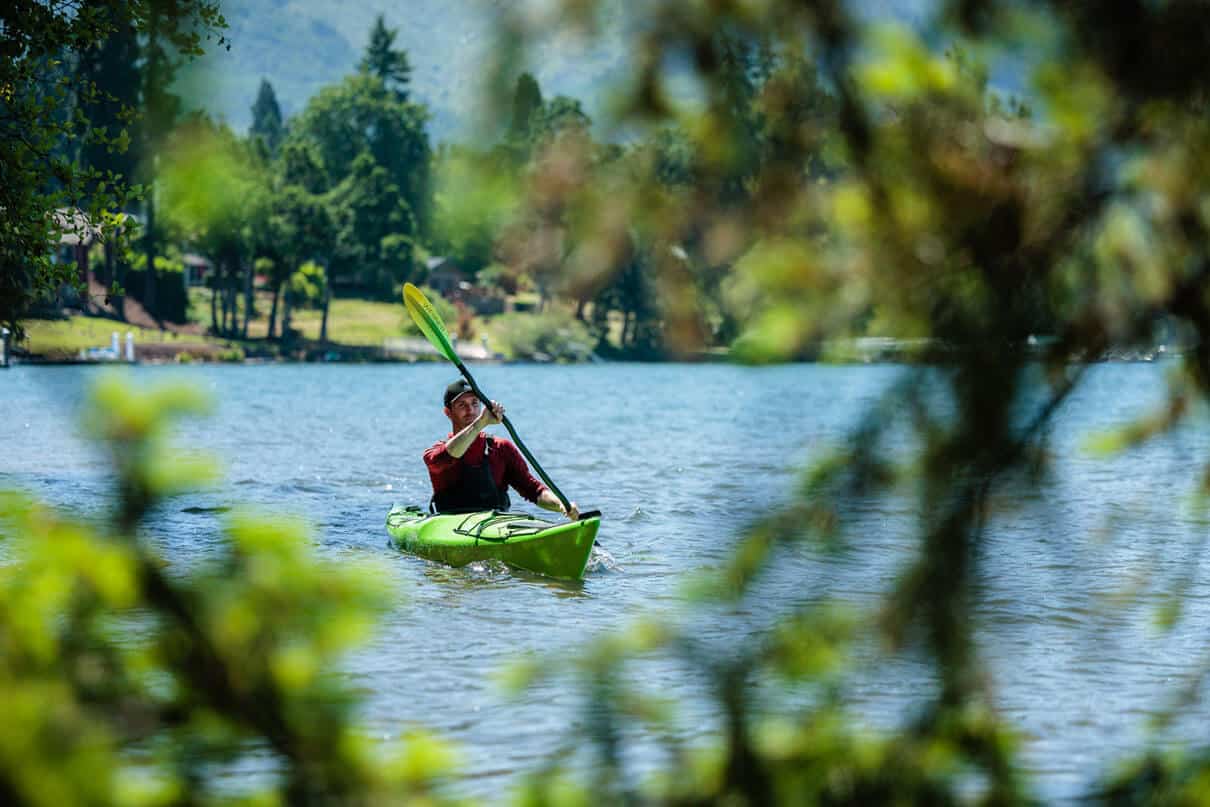 Joe Potoczak paddles the Lekker Osprey with leafy foliage in front
