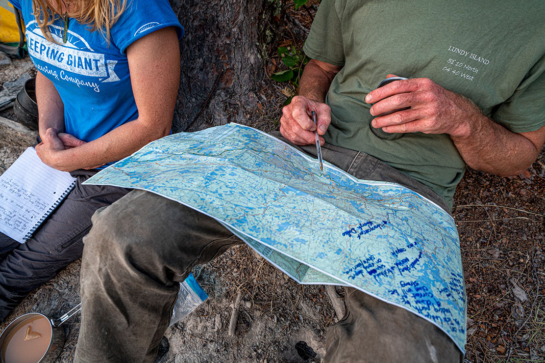 two canoeists practice their map reading skills while on trip