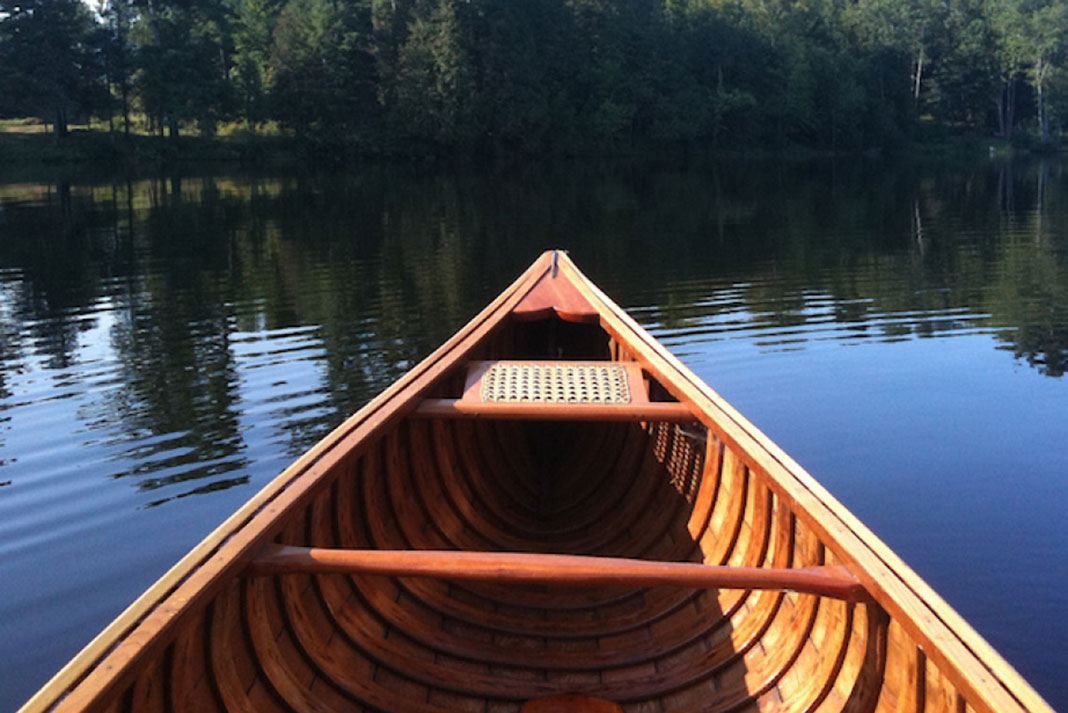 the bow of a wooden canoe on a lake