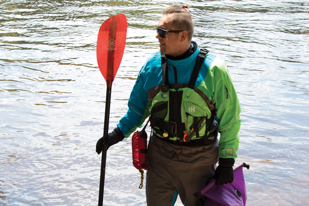 man holding a kayak paddle and wearing paddling gear