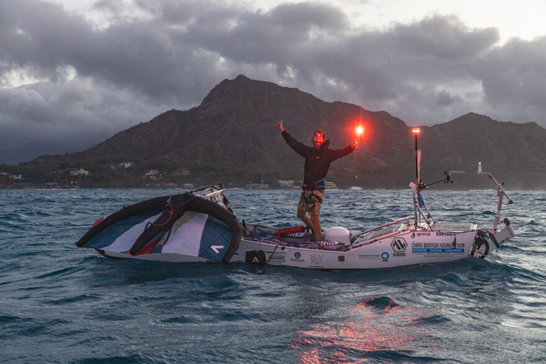 Man stands with flare on top of custom-built expedition paddleboard ready for major feats of paddling