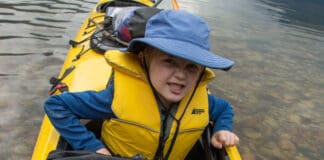 kid poses in a kayak with map
