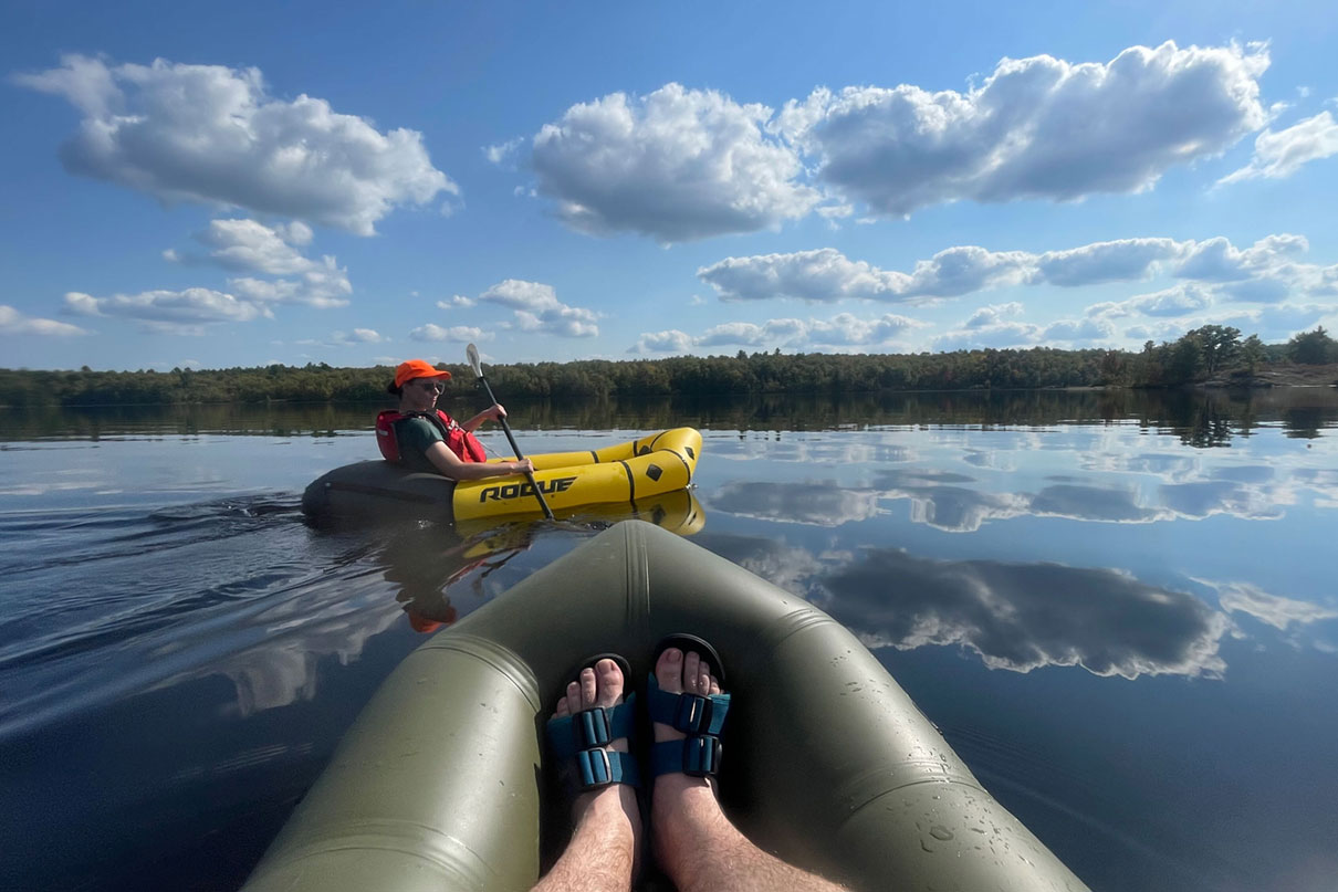 Bow shot of a packraft with person wearing Astral Webber water shoes.