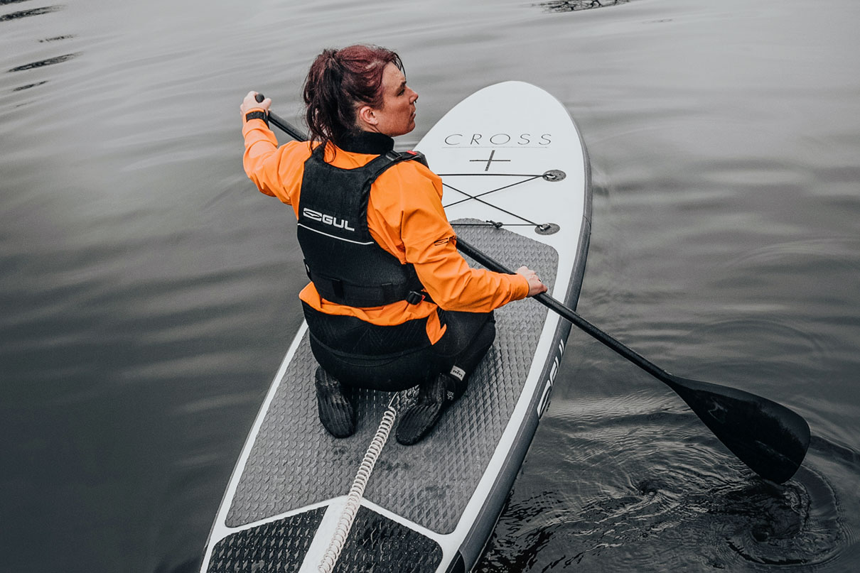 Woman paddles an inflatable paddle board while wearing GUL Power Boots.