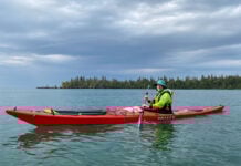 What To Wear Kayaking: The Complete Guide woman poses while sea kayaking in rainy weather