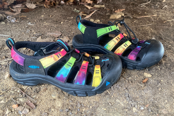 A pair of Keen Newport Retro water sandals sit on a dirt garage floor.